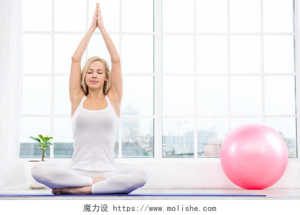 白色窗户里美丽的女人正在莲花姿势时冥想练习瑜伽产后瑜伽
